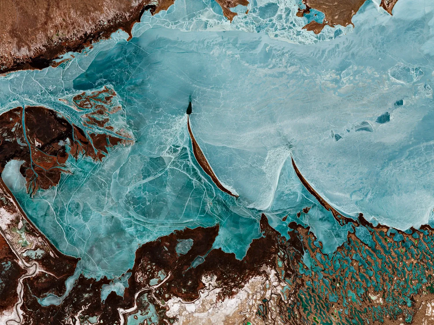 Lac Balkhash — Le lac figé par le froid offre des nuances de bleu et un réseau de fissures.