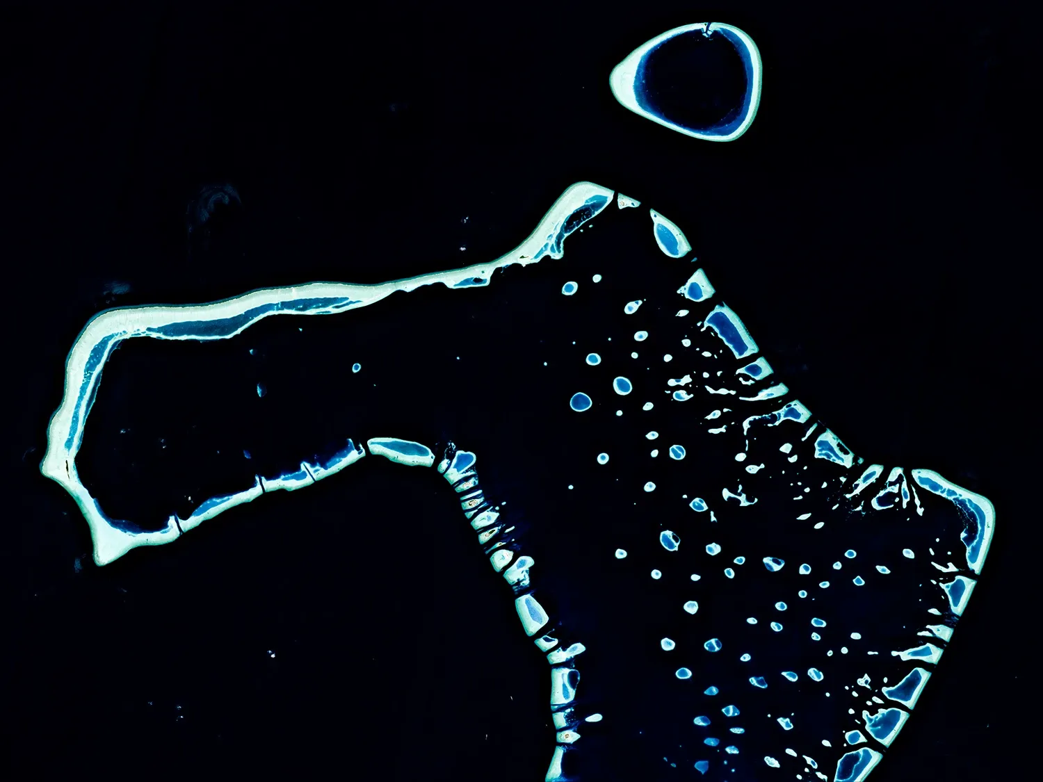 Les Maldives — Une myriade d’îles et de contours lumineux se détache de l’immensité sombre de l’océan.